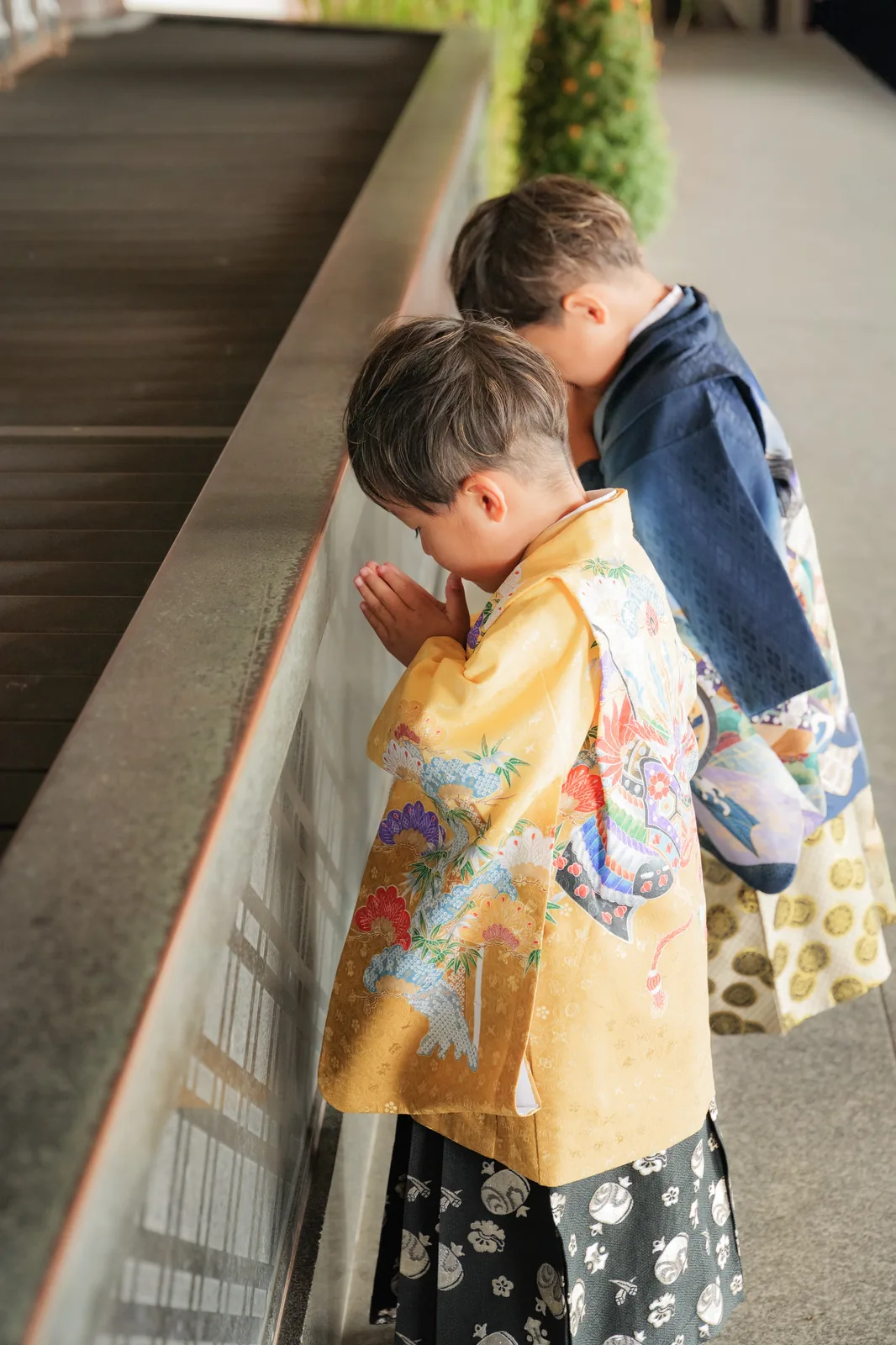 本堂の前で手を合わせてお参りする袴姿の兄弟の後ろ姿