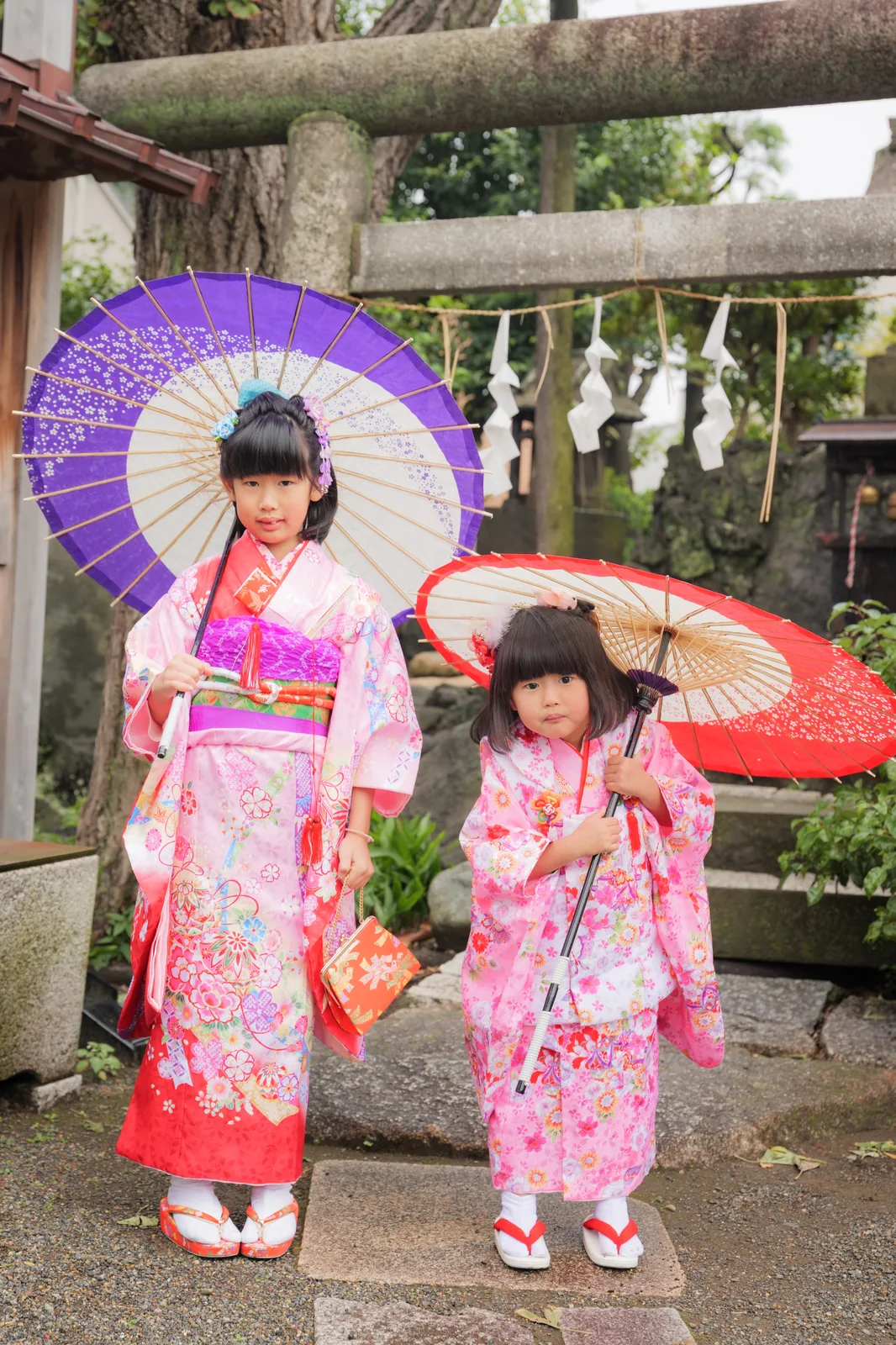 fufuの七五三撮影作例。鳥居の前で和傘を持つ着物姿の姉妹