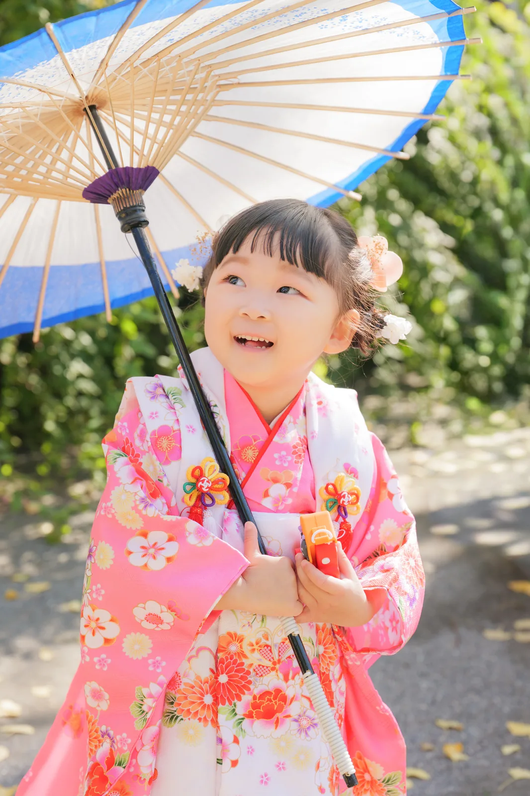 和傘を持って笑う被布姿の3歳の女の子
